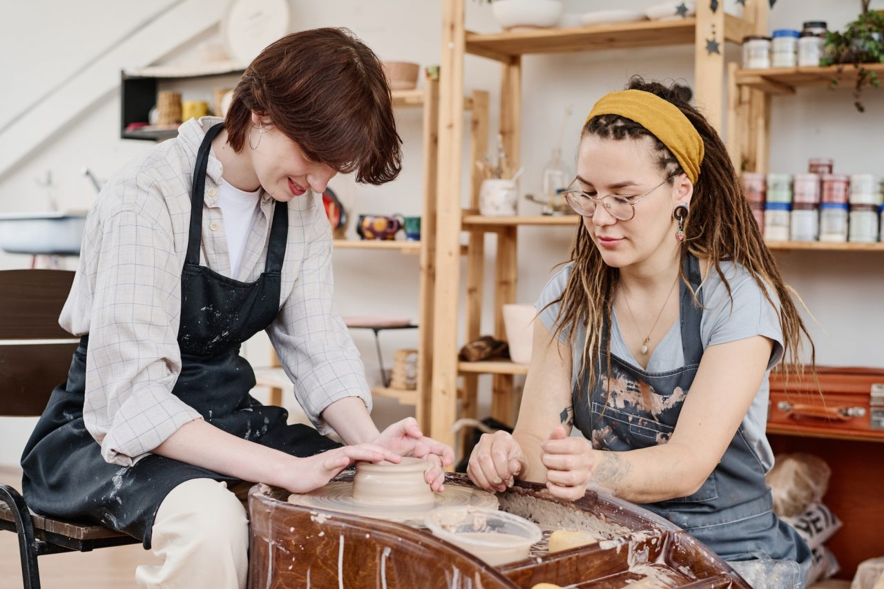 Pottery instructor helping a student at the wheel